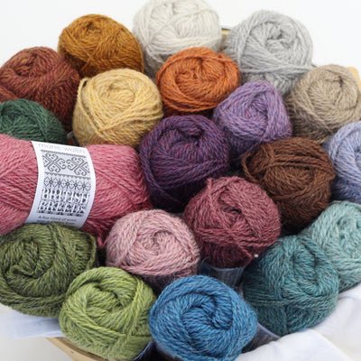 A basket of balls of Marie Wallin's British Breeds yarn, fingering weight, on a white background
