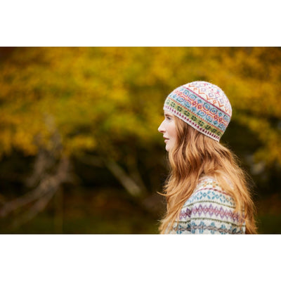 Profile view of Female model wearing Tarn Tam, an allover colorwork hat designed by Marie Wallin in her new collection, Cumbria