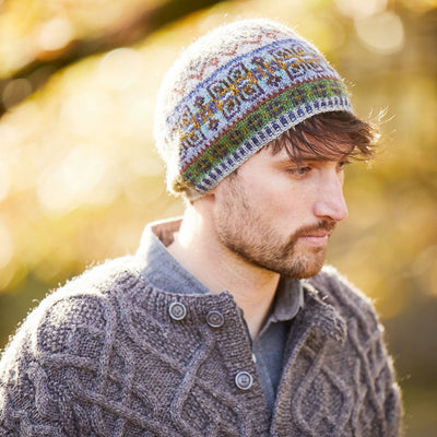 Male model wearing Tarn Tam, an allover colorwork hat designed by Marie Wallin in her new collection, Cumbria. This hat shown with Silver Birch as main color