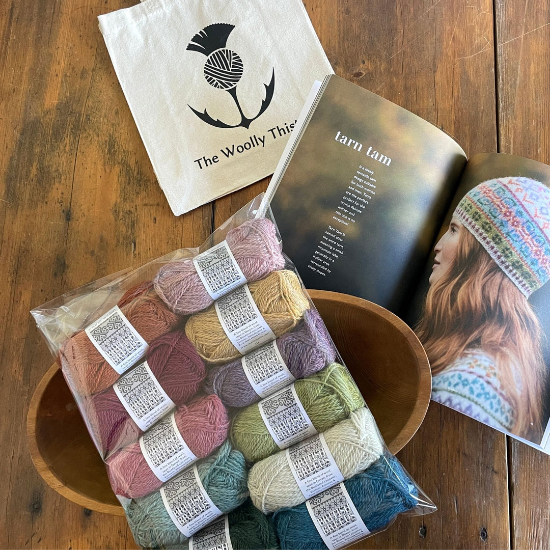 Marie Wallin's Book Cumbria open to page for Tarn Tam page with components of kit including all yarn needed to knit hat along with a Woolly Thistle Tote.