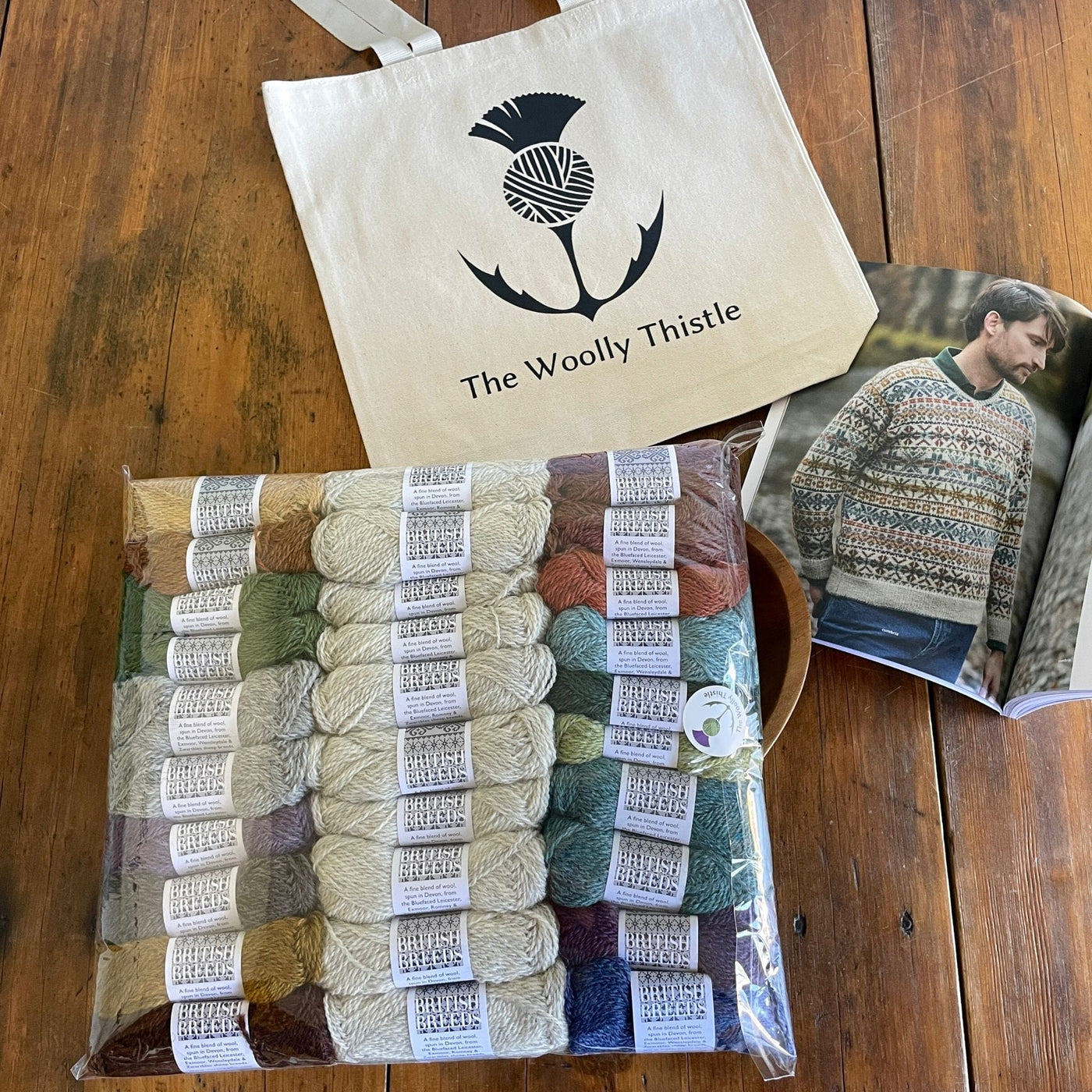 Marie Wallin's Book Cumbria open to page for Troutbeck sweater with components of kit including all yarn needed to knit sweater along with a Woolly Thistle Tote.