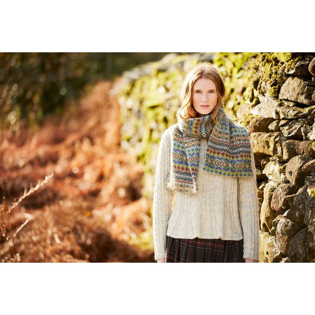 Female model standing outside wearing Swaledale, an allover colorwork scarf designed by Marie Wallin in her new collection, Cumbria