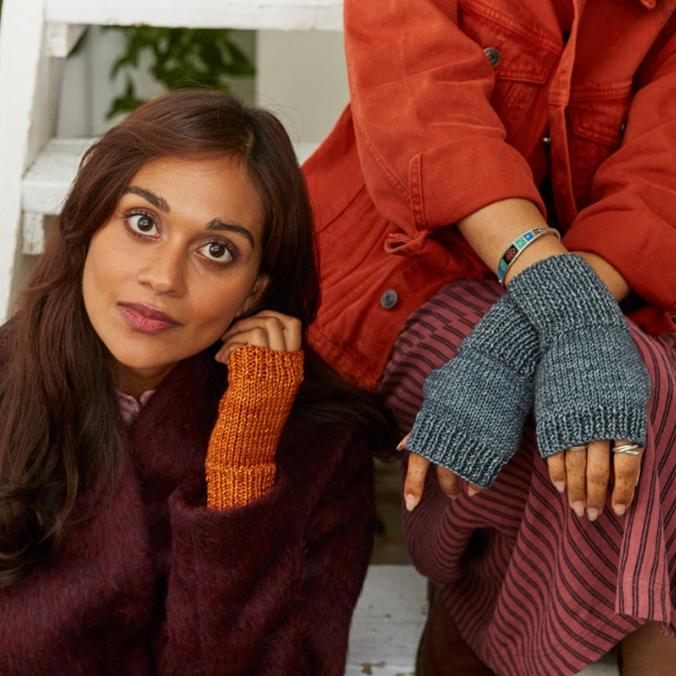Two women wearing knit fingerless mittens