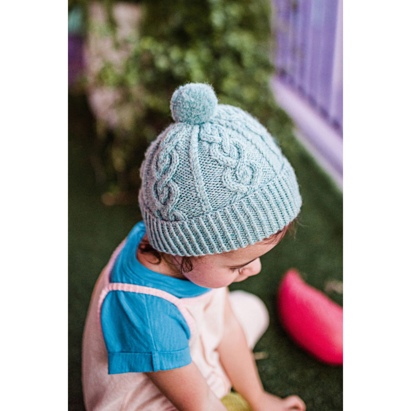 Pattern in minipom magazine shows aerial view of child wearing handknit hat with heart designs.