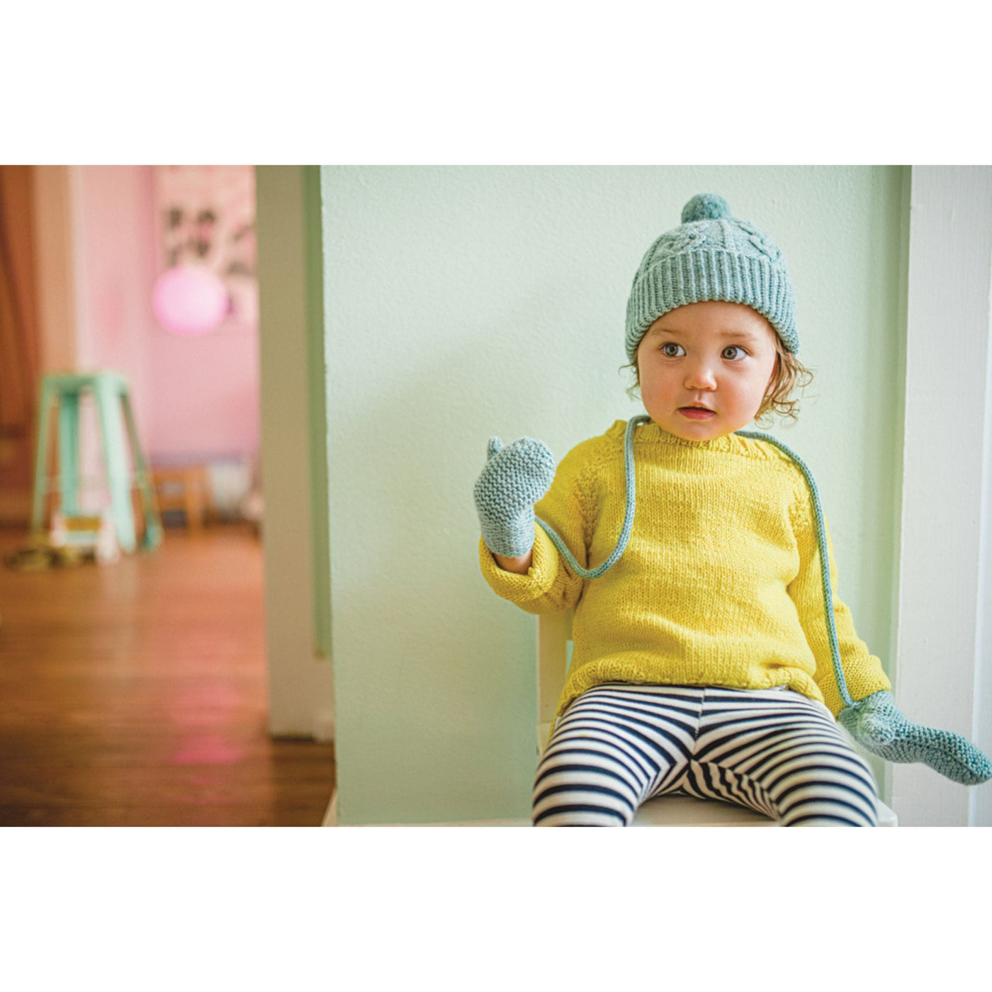 Child wearing handknit hat and mitts which are designs from Mini Pom magazine.