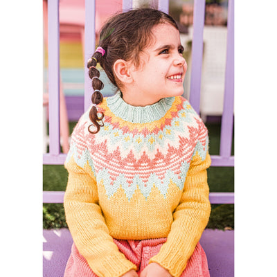 Child sitting outside in a yellow sweater with colorwork yoke. Sweater is a design from Mini Pom Magazine. 