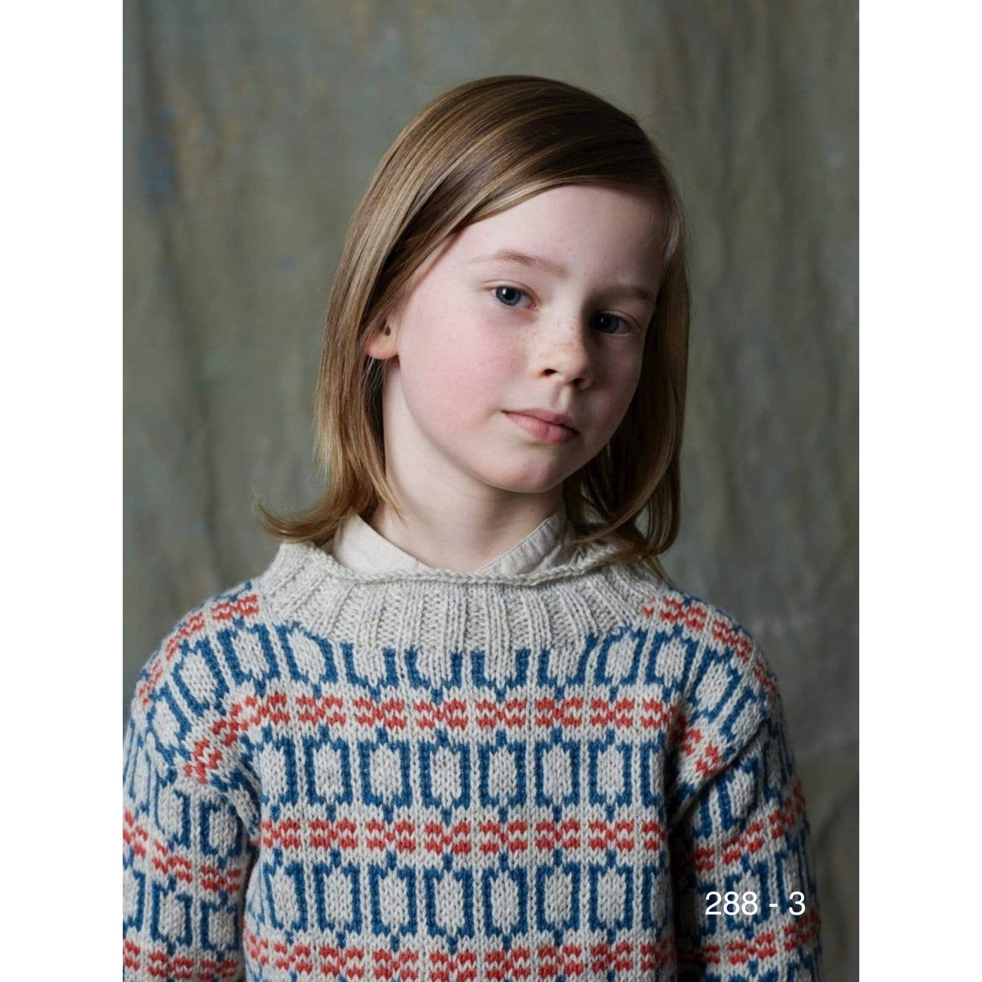 A child in an overall colorwork pullover knit in Strikkegarn using Rauma pattern 288-3.