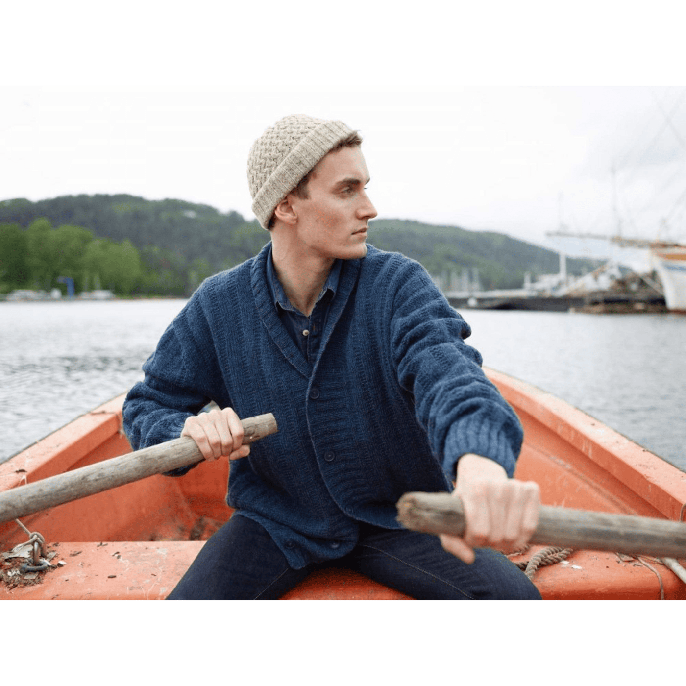 Man wearing knitted blue sweater and tan hat from Rauma Finullgarn pattern book from the Woolly Thistle