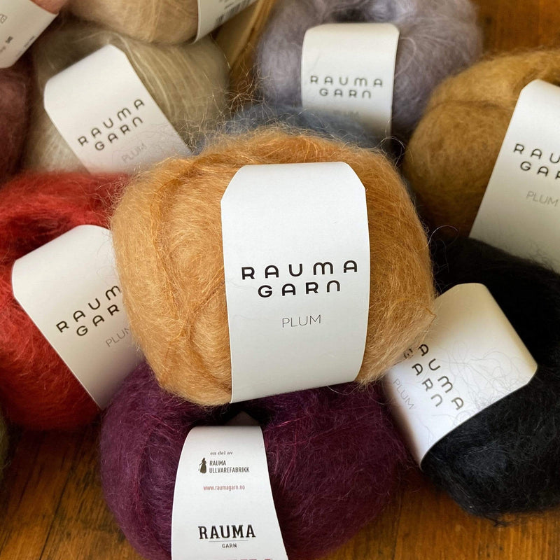 Small pile of balls of Rauma Plum yarn, a laceweight mohair, in various colors
