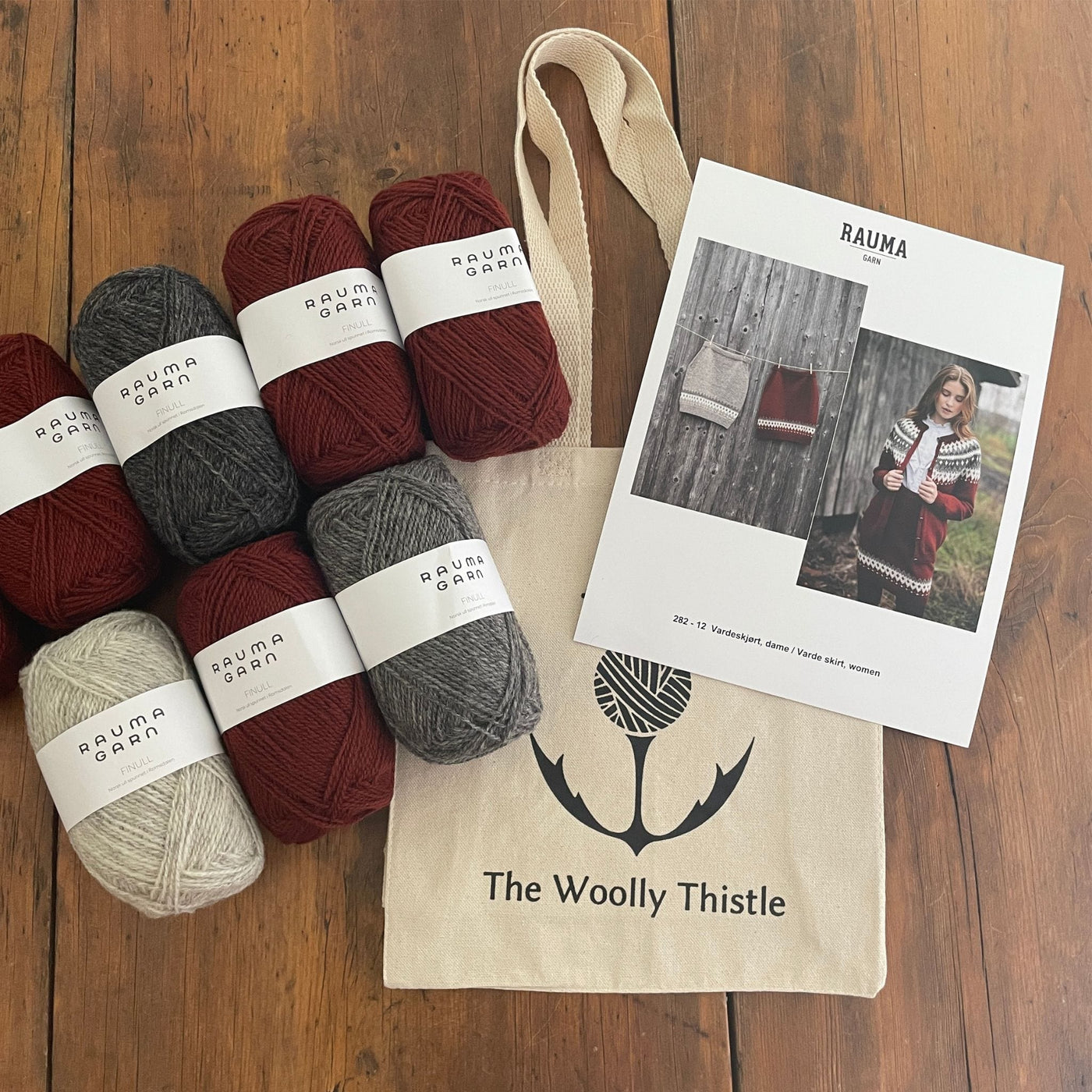 Components of the Varde Skirt Kit including pattern card, TWT Tote, and Rauma Finullgarn yarn in Burgundy and greys.