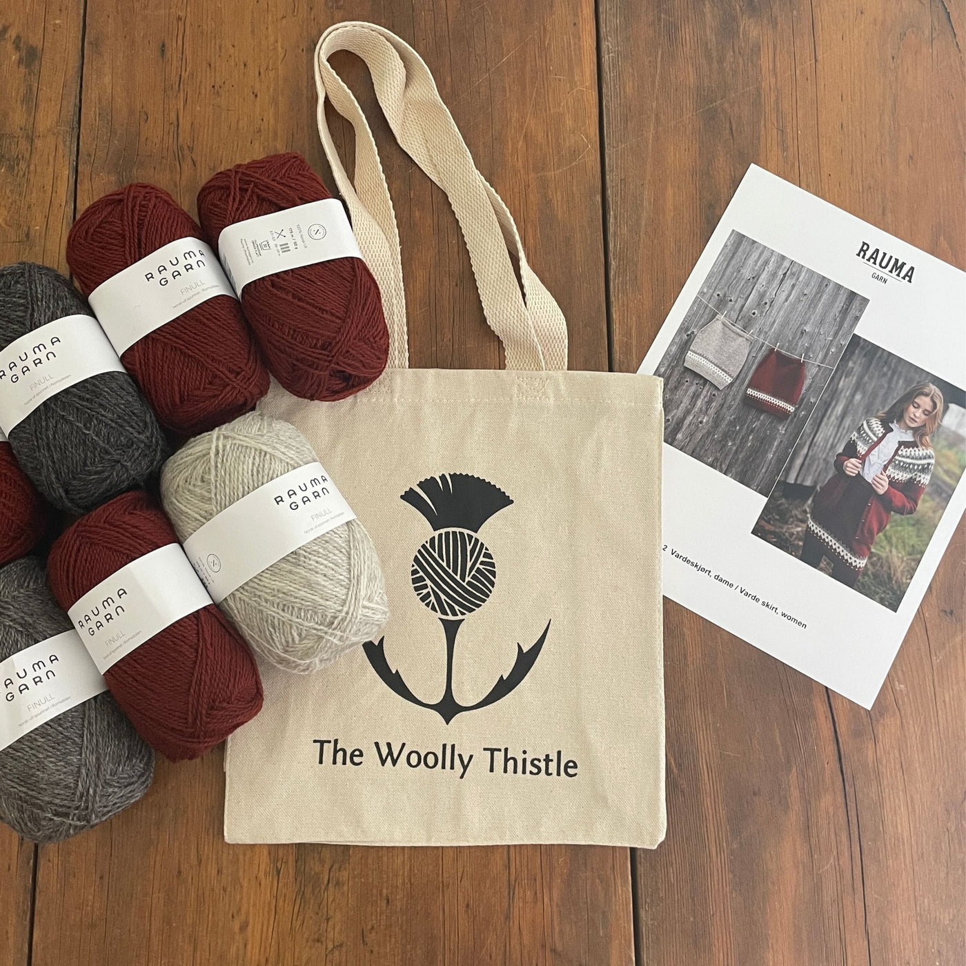 Components of the Varde Skirt Kit including pattern card, TWT Tote, and Rauma Finullgarn yarn in Burgundy and greys.