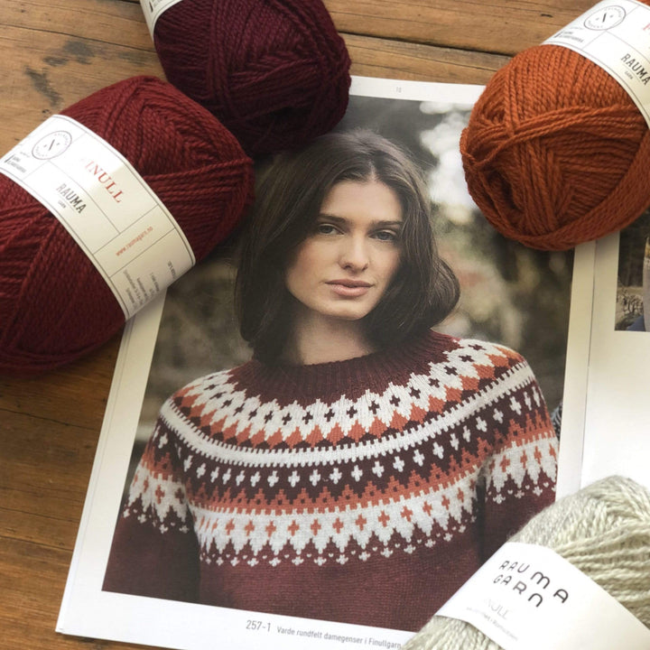 The Woolly Thistle Varde Yoke Sweater 275R in Rauma Finullgarn- sweater in patterned burgundy and 3 balls of Rauma Finullgarn yarn in burgundy, deep burgundy, and burnt orange 