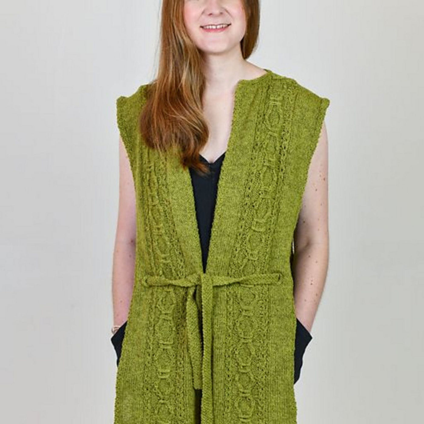 Model wearing Sìthean Tabard, a green sleeveless cardigan. Pattern from Yarn-A Journal of Scottish Yarn. 
