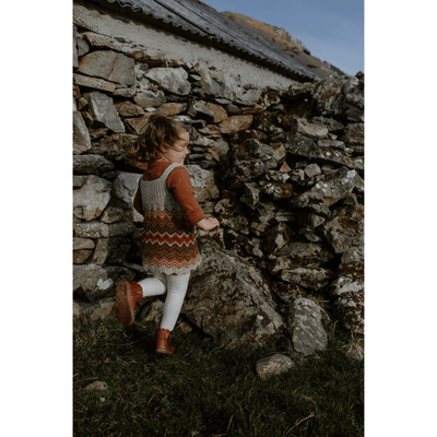 The Woolly Thistle image from Shetland Wool Week Annual 2021 featuring a girl running wearing a knitted sweater dress with fair isle  design