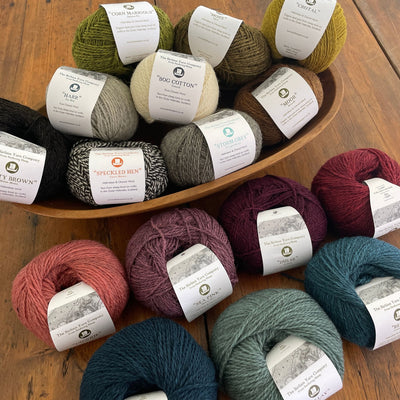 Birlinn Yarn Company Hebridean 4ply yarns shown in various colors on wooden table. 