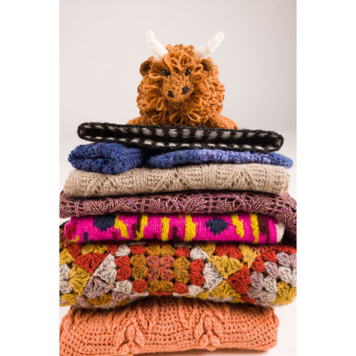 Yarn The Journal of Scottish Yarns interior page shows stack of knit and crochet items with handmade Highland Cow Toy sitting atop the pile..