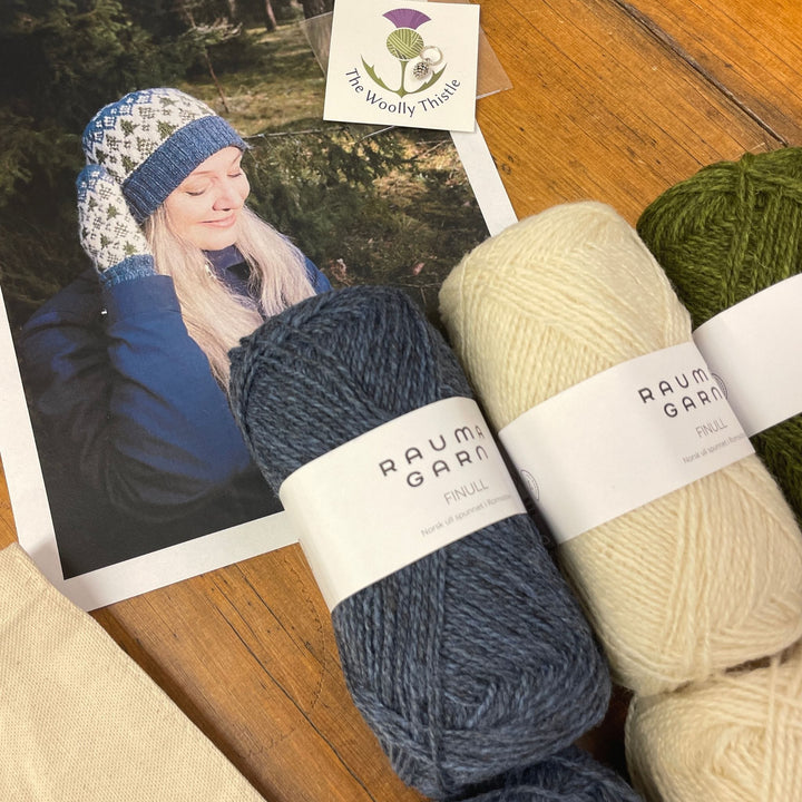 Components of the Heart of the Forest Mittens and Hat Yarn Set. Shown with a photo of the knit items and Rauma Finullgarn yarn in heathered blue, cream, and green. The Woolly Thistle Stitch Marker and Tote are visible on the edge of the photo.