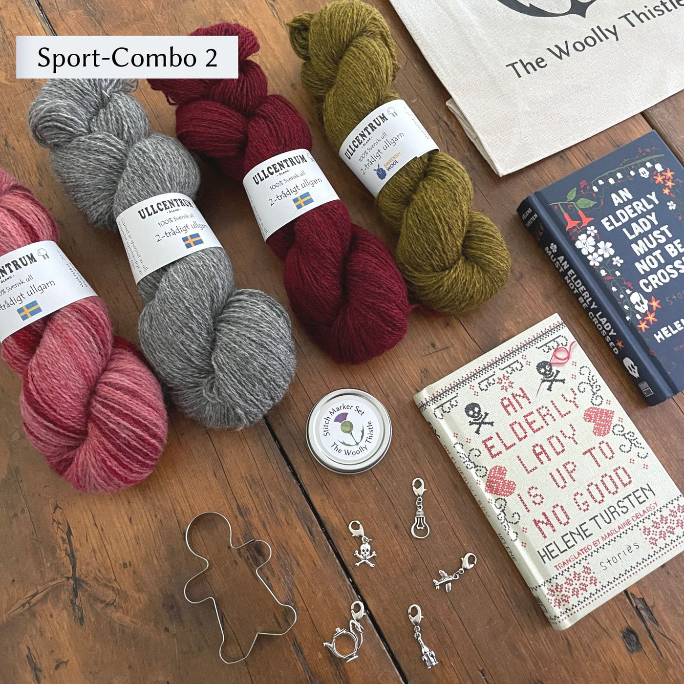 The Swedish Book Bundle components which include two books by Helene Tursten, TWT Tote bag, Stitch marker set, gingerbread cookie cutter, and Ullcentrum Sport Weight yarn. Components are shown and laid out on table. Yarn colors in Sport Combo 2 include a variegated red, grey, deep red, and gold/green.