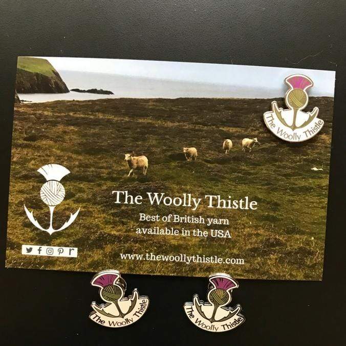 Three Woolly Thistle Enamel Pin against postcard.