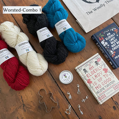 The Swedish Book Bundle components which include two books by Helene Tursten, TWT Tote bag, Stitch marker set, gingerbread cookie cutter, and Ullcentrum Worsted Weight yarn. Components are shown and laid out on table. Colors in Worsted Weight Combo 1 include a red, cream, dark grey, and teal. 