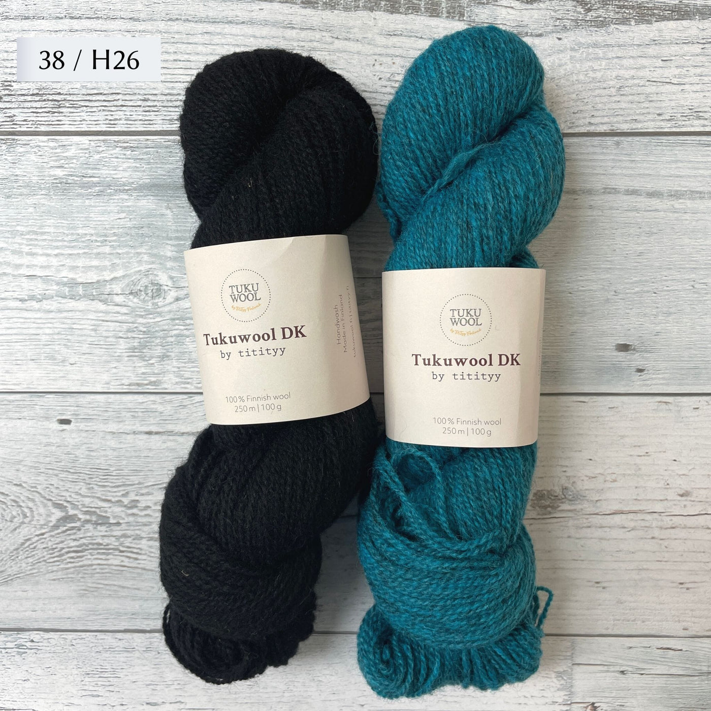 Two Skeins of Tukuwool DK shown as a colorway option for the Muisto Hat & Mittens Set. 38 (black) and H26 (heathered turquoise.)
