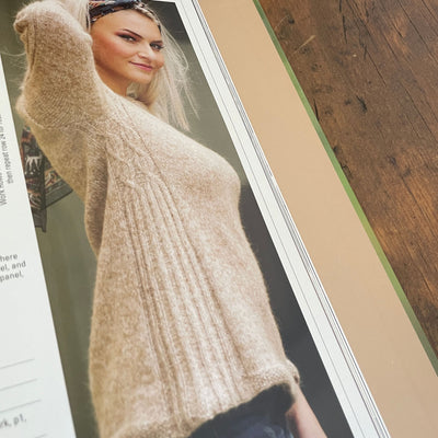 Inside pages of book Norwegian Sweaters & Jackets by Kari Hestnes shows woman wearing beige sweater showing side and arm detail and texture. 