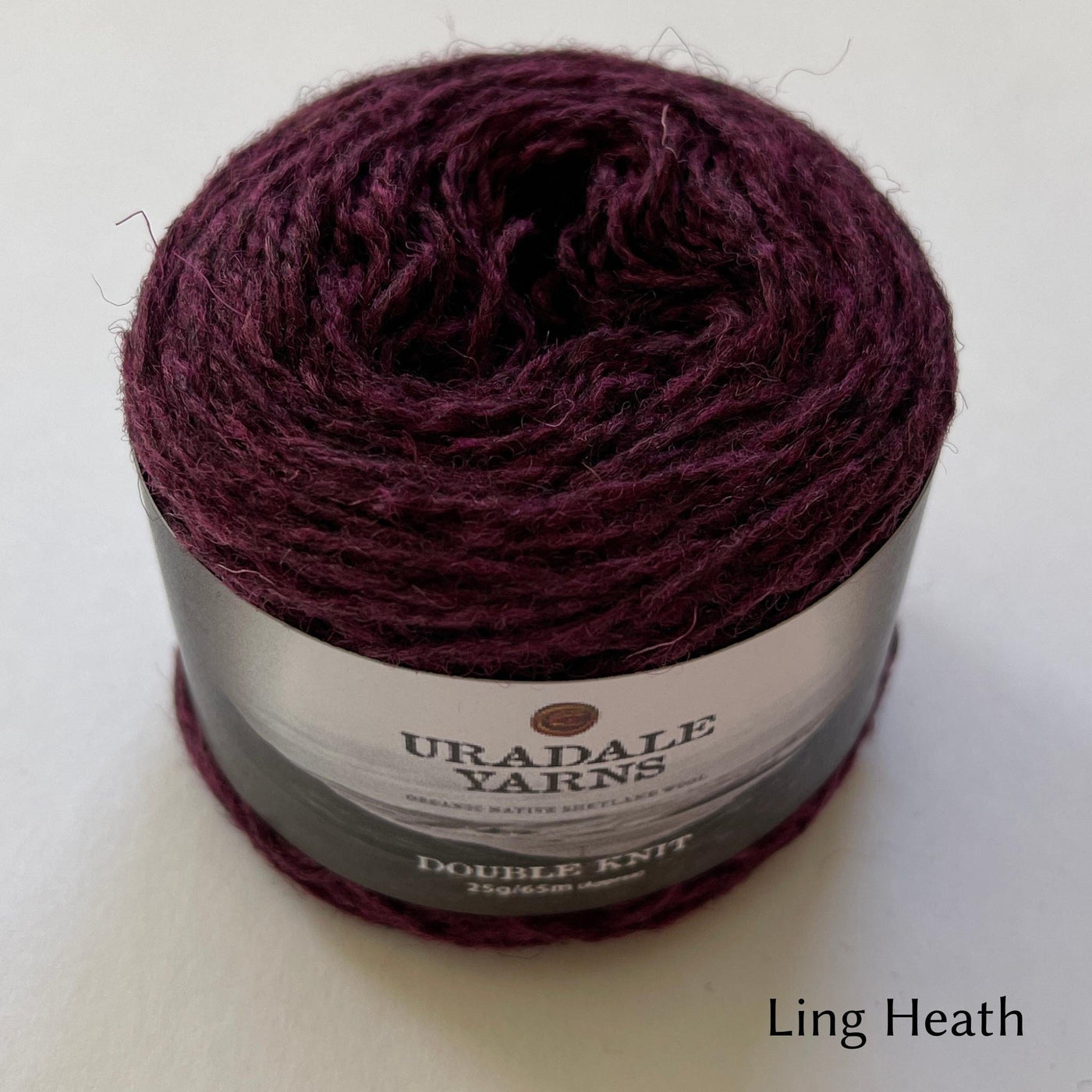 cake of Uradale DK yarn in color Ling Heath- heathered burgundy