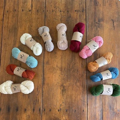 An array of WoolDreamers Dehesa de Barrera, a fingering weight yarn, on a wooden floor