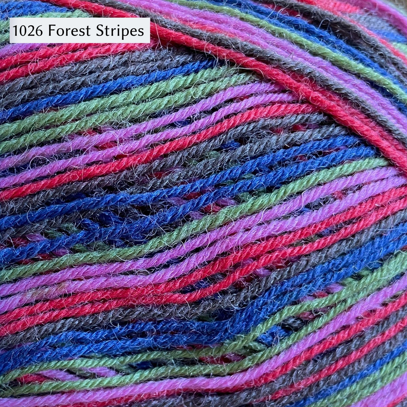West Yorkshire Spinners Signature 4ply yarn, fingering weight, in color 1026 Forest Stripes, with even stripes of royal blue, light green, grey, pink, and red