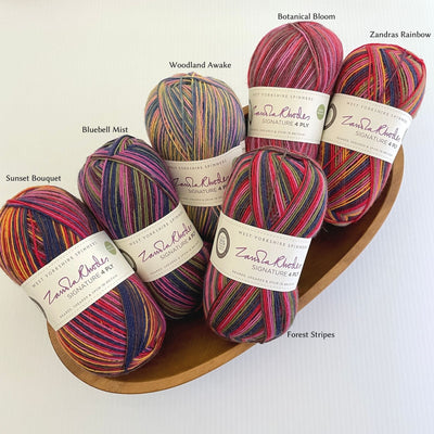 Six Zandra Rhodes colorways of West Yorkshire Spinners Signature 4ply yarn, fingering weight, in a wooden bowl on a white surface
